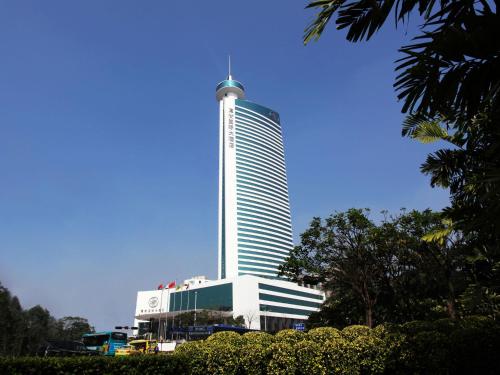 a tall white building with a tower at HJ International Hotel in Dongguan