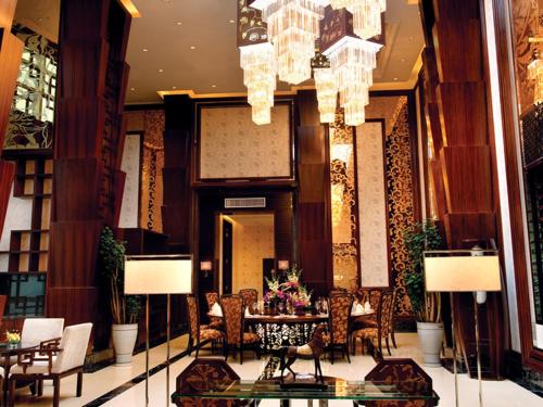 a lobby with a table and chairs and chandeliers at HJ International Hotel in Dongguan