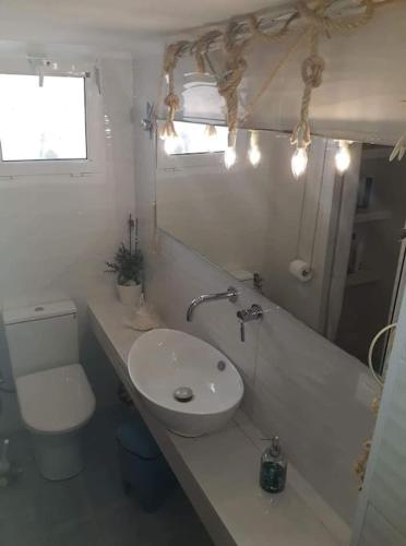 a white bathroom with a sink and a toilet at Any Summer garden house in Skála Nikíta