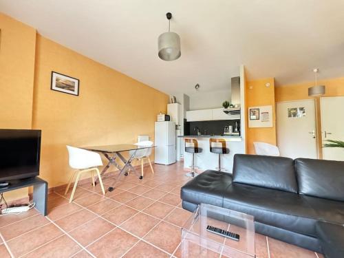 a living room with a black leather couch and a table at Bel appartement spacieux 2 pers avec Balcon - Thermale 3 in Chamalières