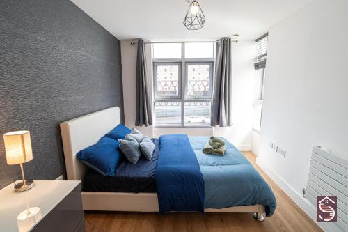 a bedroom with a blue bed and a window at The Canning Comfort in London