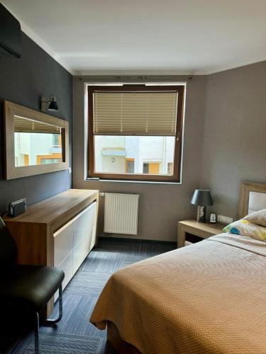 Un dormitorio con una cama y un escritorio y una ventana. en Apartament przy plaży, en Władysławowo