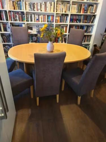 a table in a library with chairs and a vase on it at North Edinburgh - Shared house bwith own room and bathroom in Edinburgh