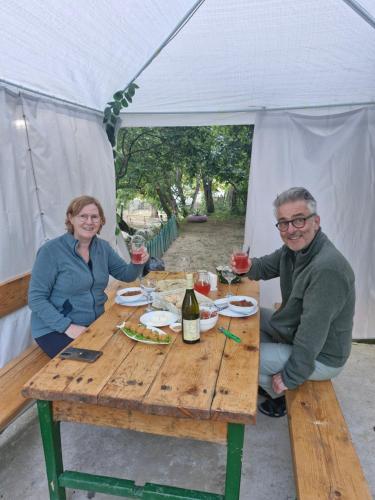 a man and woman sitting at a wooden table with wine glasses at LeriMari in Mestia