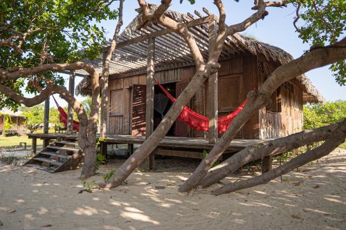 a wooden shack with a red hammock in front of it at Vila Guará in Atins