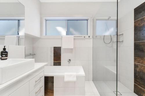 a white bathroom with a shower and a sink at TWELVE at 12 Private Central Maroochydore in Maroochydore