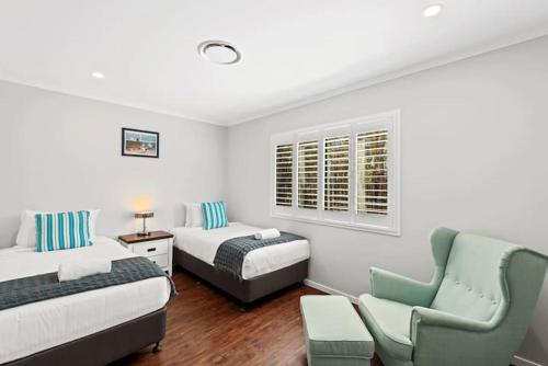 a bedroom with two beds and a couch and a chair at Private Mudjimba Beach Abode in Mudjimba