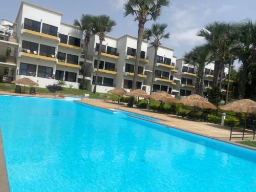 a large blue swimming pool in front of a building at WATERFRONT FLAT 4 BEDROOM in Kololi