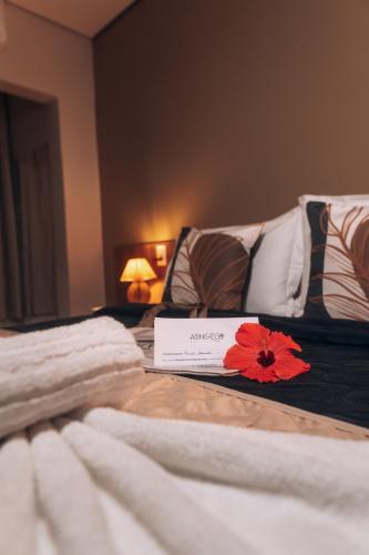 two beds with white blankets and a red flower on them at Pousada Aconchego Noronha in Fernando de Noronha