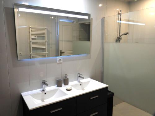 une salle de bain avec un lavabo et un miroir dans l'établissement les volets bleus, à Lamalou-les-Bains