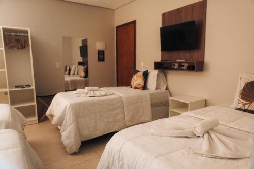 a hotel room with two beds and a flat screen tv at Pousada Aconchego Noronha in Fernando de Noronha