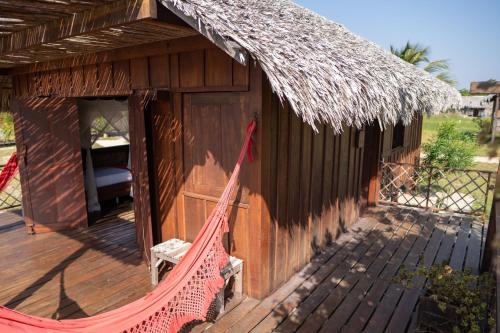 a hammock in front of a hut with a thatched roof at Vila Guará in Atins