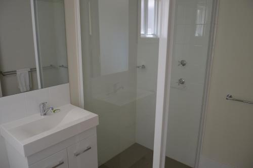 a white bathroom with a shower and a sink at BATHURST GOLDFIELDS RESIDENCE on MOUNT PANORAMA in Bathurst