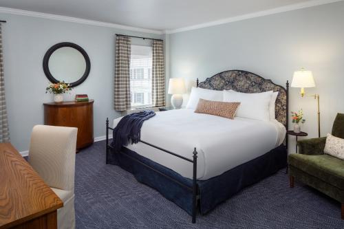 a bedroom with a bed and a chair and a mirror at Colgate Inn in Hamilton