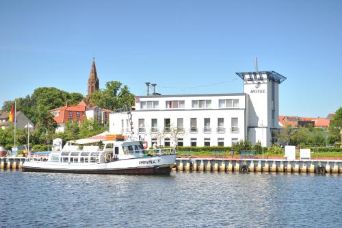 Ein Boot liegt im Wasser in der Nähe eines Gebäudes. in der Unterkunft HafenHotel PommernYacht in Ueckermünde