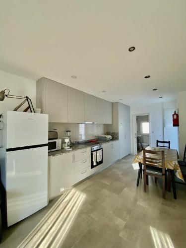 a kitchen with a table and a white refrigerator at Casinha dos Carris in Valença