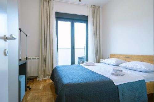een slaapkamer met een bed met een groot raam bij Apartman 20 in Trebinje