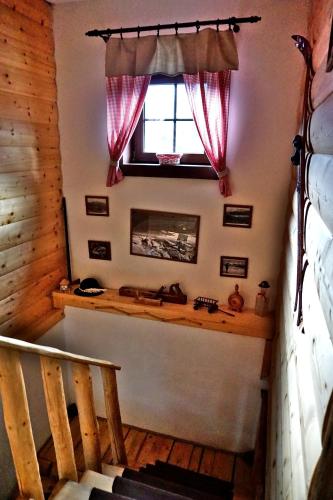 a room with a staircase and a window with red curtains at Bačova drevenica in Liptovský Ján