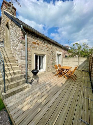 une terrasse en bois avec une table et des chaises et un bâtiment dans l'établissement Un petit nid de paradis, à Pléneuf-Val-André