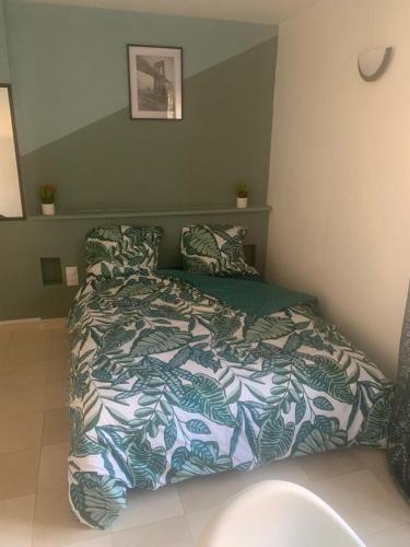 - une chambre avec un lit et une couette verte et blanche dans l'établissement FOTOU Place, à Sarcelles