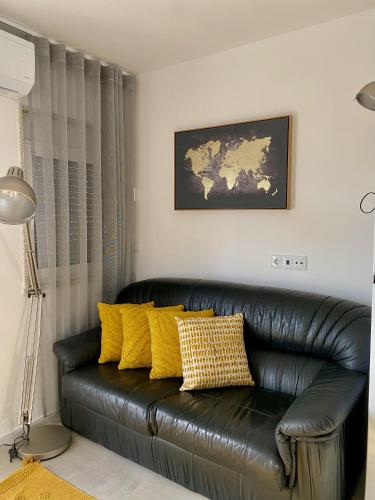 a black leather couch with yellow pillows in a living room at Casinha dos Carris in Valença