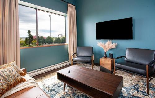 a living room with a couch and chairs and a tv at The Intrepid Rentals in Duluth