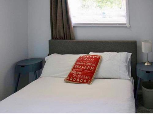 a bed with a red pillow sitting on top of it at Norfolk Nest 2 bedroom chalet new media wall in Hemsby