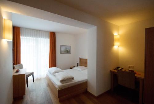 a bedroom with a bed and a desk and a window at Gasthof zum goldenen Löwen in Nauders