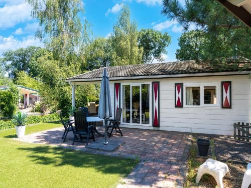 a patio with a table and chairs and an umbrella at Holiday Home in Voorthuizen near Veluwe Forest in Voorthuizen