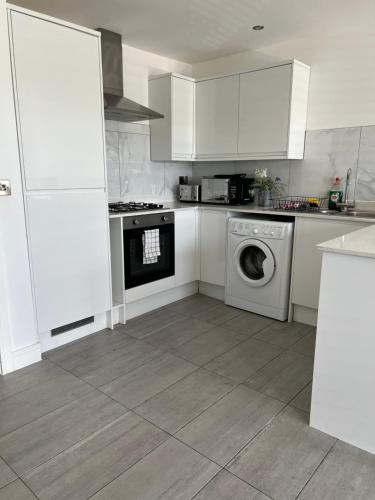 a kitchen with white cabinets and a washing machine at Modern and Stylish Two Bedroom Flat in Oxford