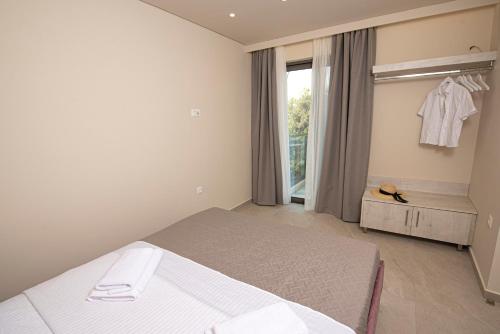a white bedroom with a bed and a window at Avali Deluxe Apartments in Lygia