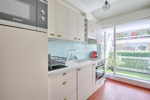 une cuisine avec des placards blancs et une grande fenêtre dans l'établissement Saint Dominique - Perfect location - Eiffel Tower, à Paris