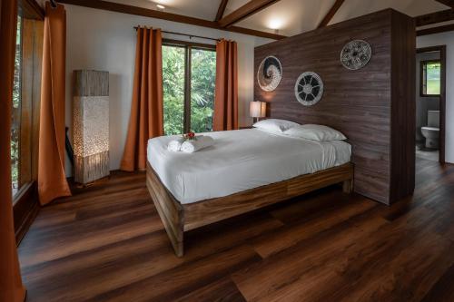a bedroom with a large bed with wood floors and a window at Beqa Lagoon Resort in Beqa Island