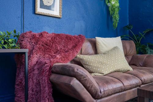 a brown leather couch with a pink blanket on it at Remodeled Apartment Blocks from Downtown Bristol in Bristol