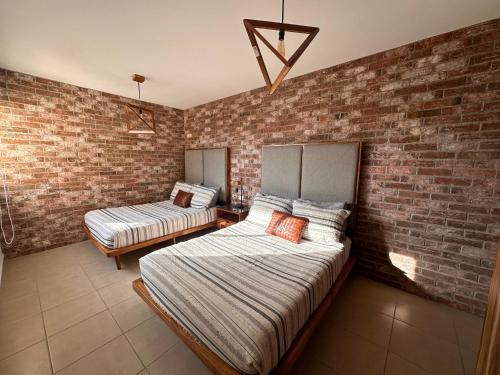 a bedroom with two beds and a brick wall at Hermosa Villa Acapulco Zona Diamante in Acapulco