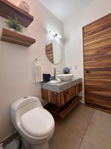 a bathroom with a white toilet and a sink at Hermosa Villa Acapulco Zona Diamante in Acapulco