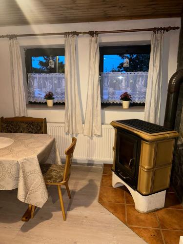 a living room with a stove and a table and windows at U krbu in Jindřichovice