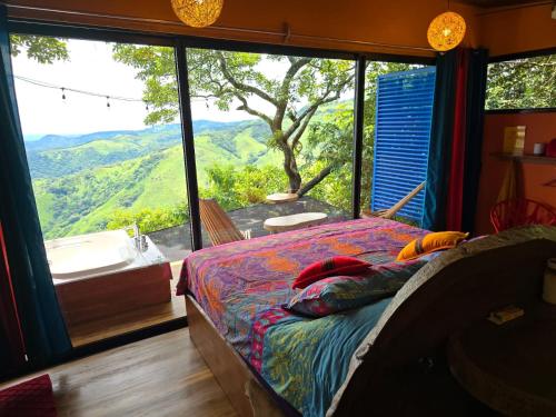 a bedroom with a bed and a large window with a view at El Sol Monteverde in Monteverde Costa Rica