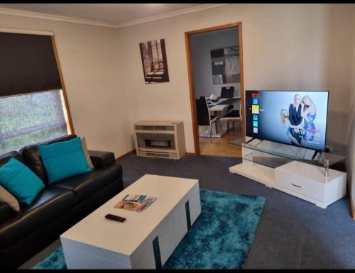 a living room with a couch and a flat screen tv at WI -FI- Netflix- Super Comfiest 3 Bedroom Home With Massive 21Metre Driveway Space for boat & Caravan in Portland
