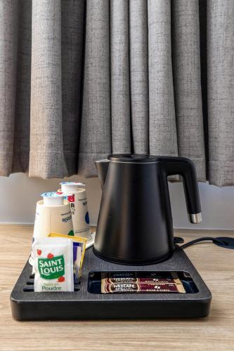 a black tea kettle on a tray on a table at Campanile NATURE - Bordeaux Sud Pessac in Pessac