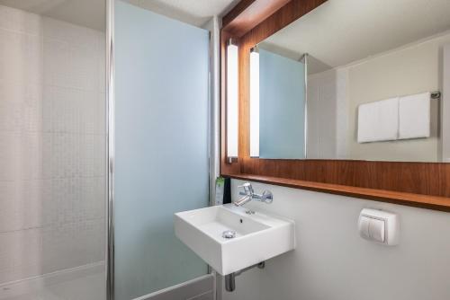 a bathroom with a sink and a mirror at Campanile NATURE - Bordeaux Sud Pessac in Pessac