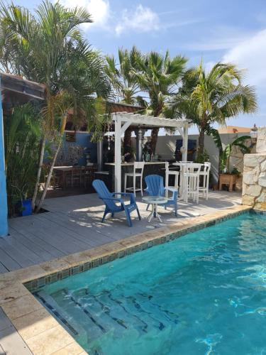 a swimming pool with two blue chairs and a table and a pool at Sandcastle Beach Apartments in Palm-Eagle Beach