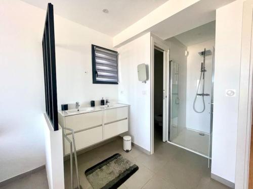 une salle de bain blanche avec un lavabo et une douche dans l'établissement Villa Pietrosella, vue sur la baie d'Ajaccio, à Agnarelu