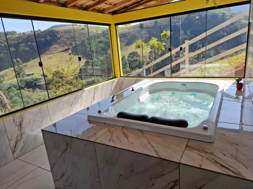 a jacuzzi tub in a room with large windows at Sítio Ramos casa amarela in Cunha
