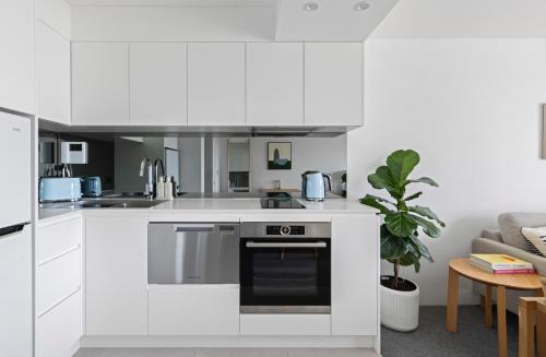 a white kitchen with a sink and a stove at The Little Beachside Apartment in Sydney
