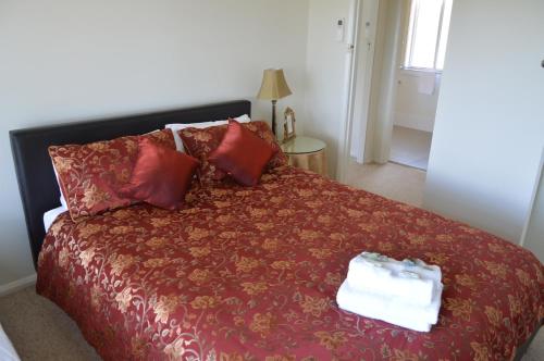 巴瑟斯特BATHURST GOLDFIELDS RESIDENCE on MOUNT PANORAMA的一间卧室配有一张带红色毯子和枕头的床。