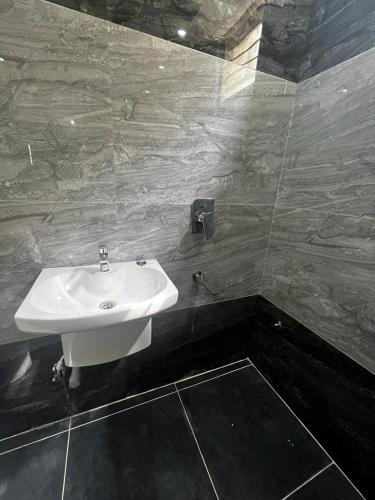 a bathroom with a white sink and a tiled wall at SSV Home stay in Tirupati