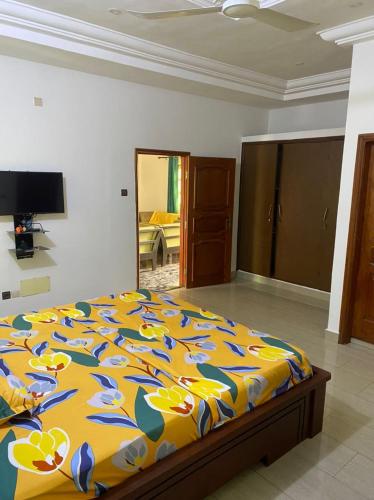a bedroom with a bed with a yellow and blue comforter at Maison Pascal in Godomè
