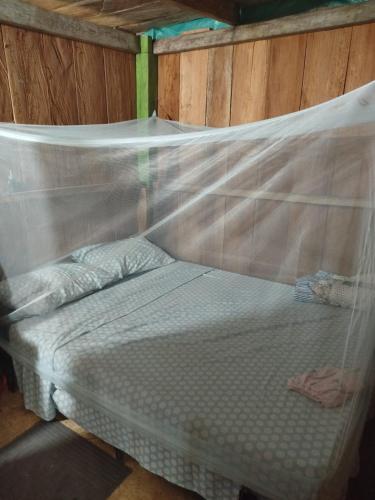 a bed with a mosquito net in a room at Posada Las Peñitas in Nuquí
