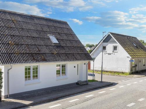 a white house with a black roof on a street at 4 star holiday home in Farsø-By Traum in Års